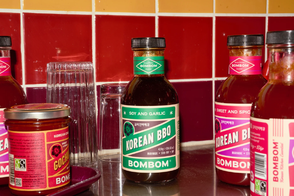 Bottles of BOMBOM BBQ sauce on counter in front of red tiled wall