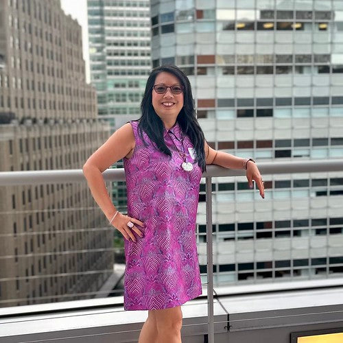 Woman in purple dress standing on a rooftop with buildings behind her