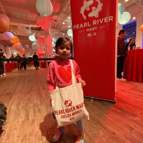 Cute little with Pearl River Mart Chelsea Market tote bag in front of Pearl River Mart pull-up banner