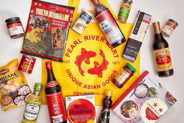 Artful arrangement of essential Asian cooking items around a yellow and red Pearl River Mart tote bag