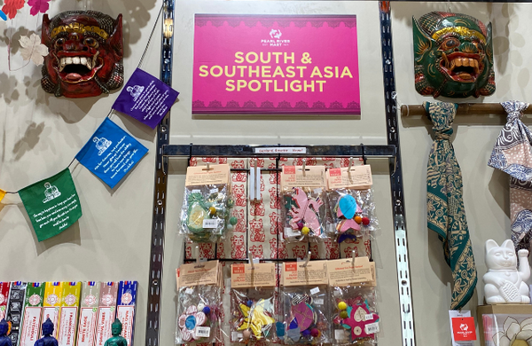 Pink sign between 2 Indonesian masks above garland display