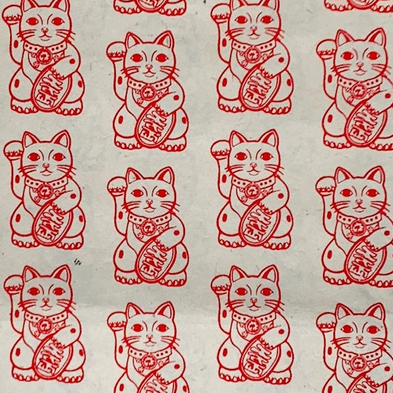 Repeating red-and-white maneki-neko, or lucky cat, illustrations cover a pale background, creating a cheerful, traditional Asian pattern.
