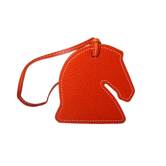 Orange horse-shaped luggage tag on a white background