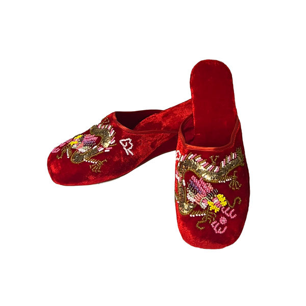 A pair of red velvet slip-on mule slippers decorated with intricate embroidered dragon motifs in gold, pink, and white thread, set against a plain white background.