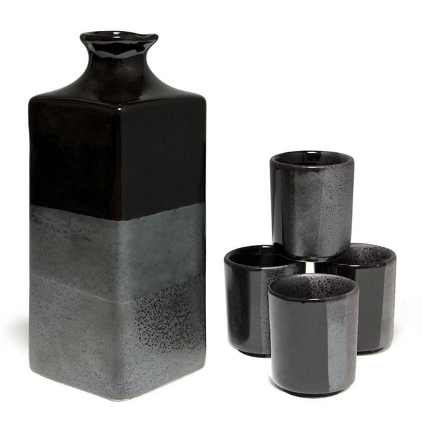 Black and gray ceramic sake bottle and three cups on a white background