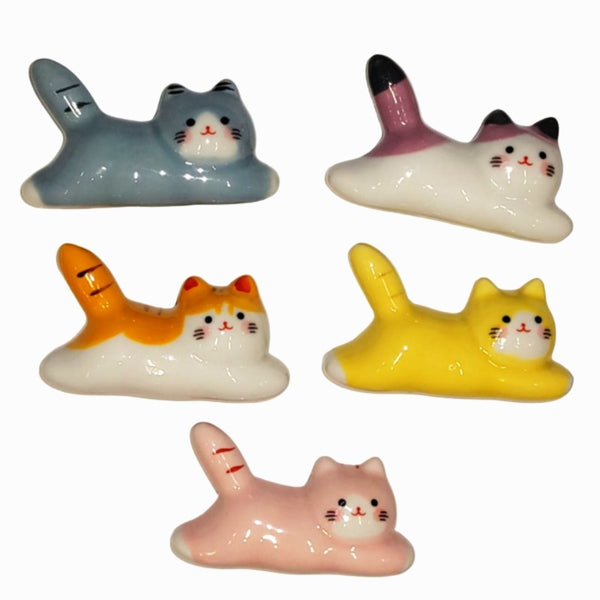 Five ceramic cat figurines in different colors on a white background