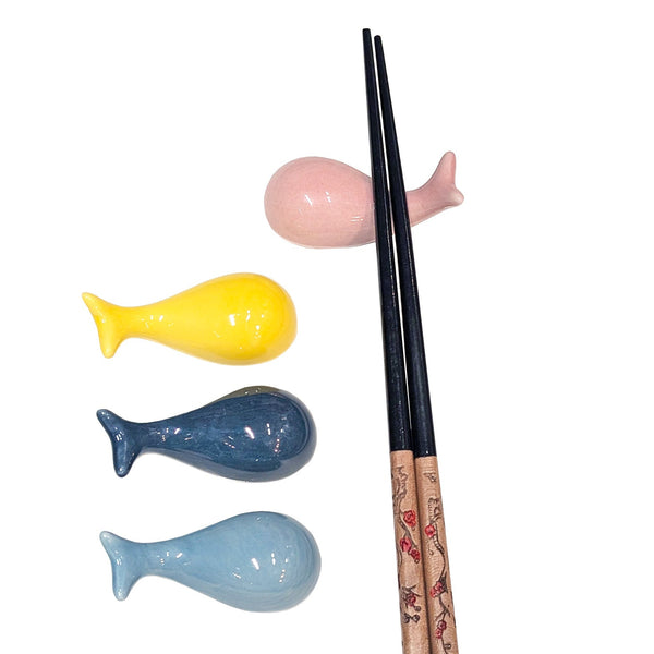 Ceramic whale chopstick rests in pink, yellow, dark blue, and light blue with one pair of chopsticks