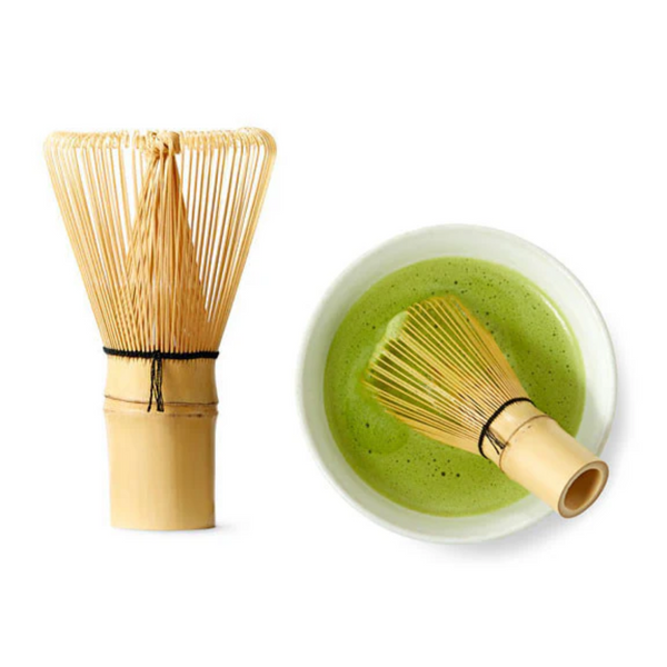 Bamboo whisk and bowl with green tea on a white background