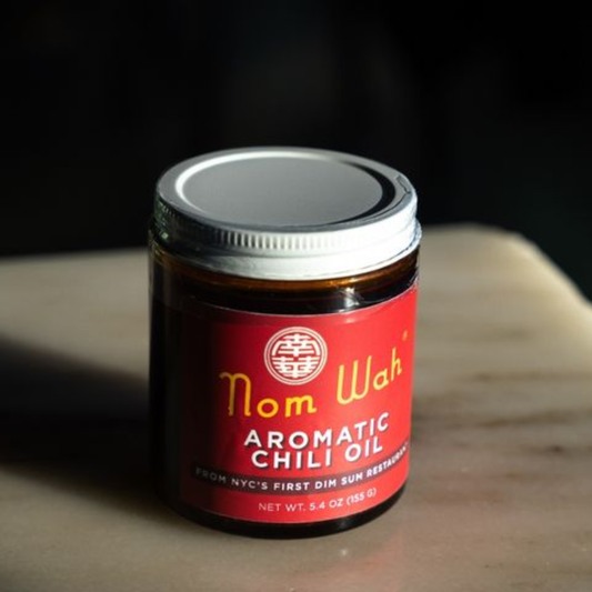 Jar of Nom Wah Aromatic Chili Oil on a wooden surface with a dark background