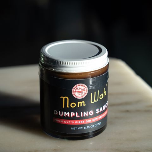 Jar of Nom Wah Dumpling Sauce on a wooden surface with a dark background