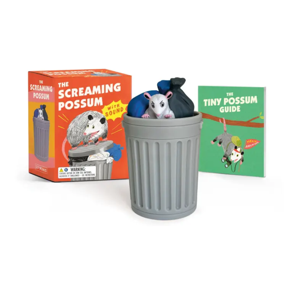 Toy possum in a trash can with packaging and book on a white background