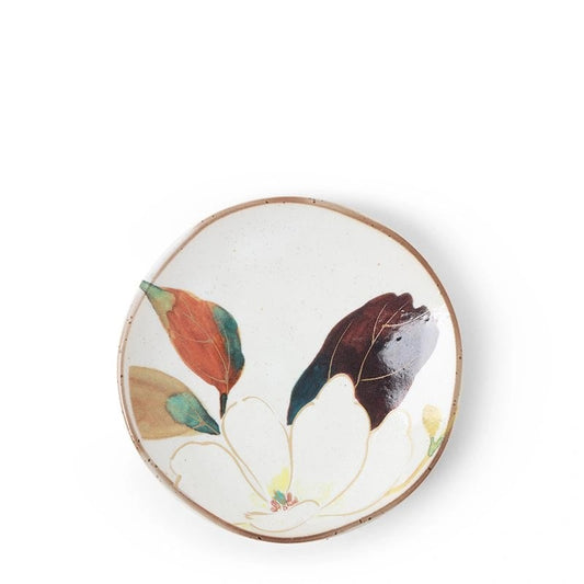 A small ceramic plate with a floral design, predominantly white flowers and green and purple leaves with a brown rim.