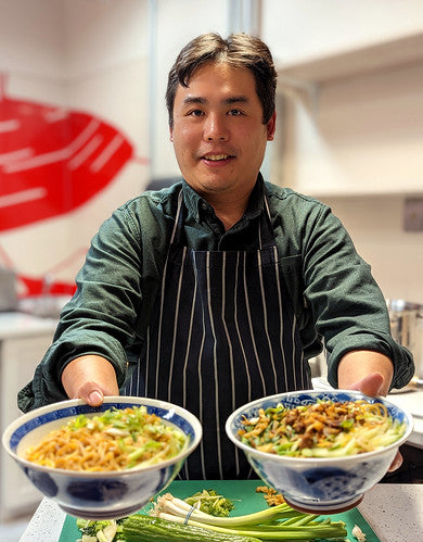 Gilley Tang holding two bowls of noodles