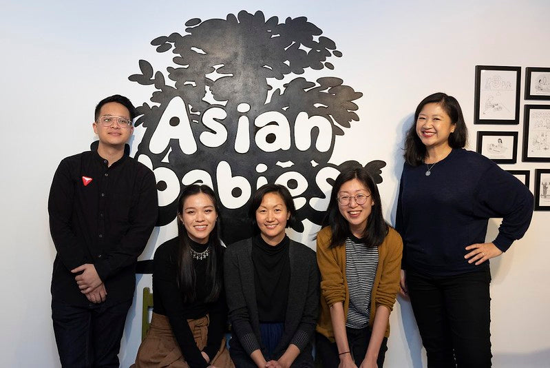 The curators and two artists for the Asian Babies exhibition, along with Pearl River Mart president Joanne Kwong, in front of tree mural in the Pearl River Mart gallery