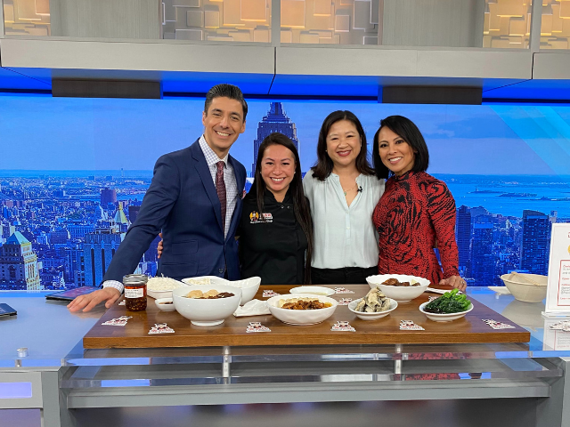 PIX11 news anchor Dan Mannarino, Maxi Lau, Joanne Kwong, PIX11 news anchor Hazel Sanchez in PIX11 studio in front of table of food 