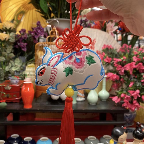 White brocade rabbit against background of vases and flowers