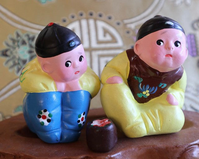 Clay figurines of two boys in traditional Chinese clothing with wary expressions