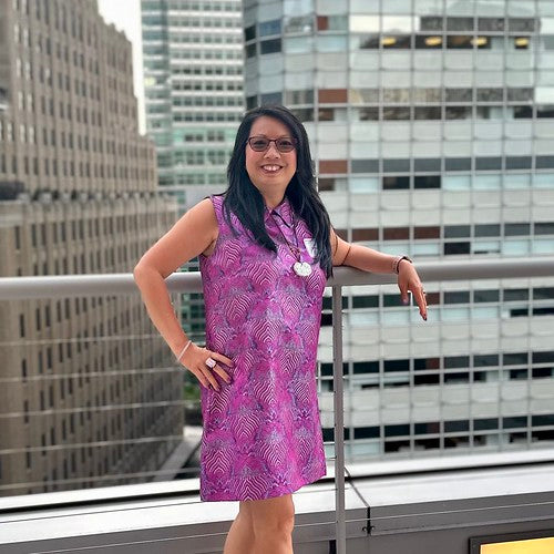 Woman in purple dress standing on a rooftop with buildings behind her