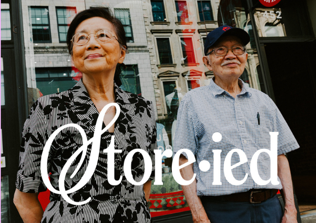A woman and man standing in front of a storefront with text