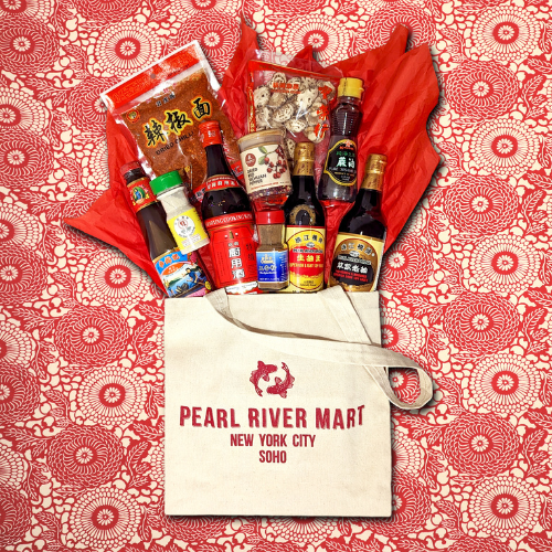 Various Asian ingredients "spilling" out of Pearl River Mart tote bag on red and white background