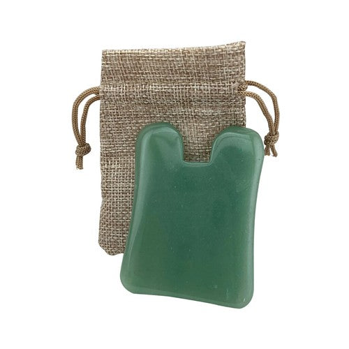 Green gua sha stone on top of burlap bag