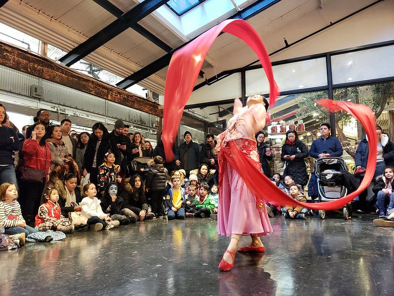 A Chinese ribbon dancer in a dramatic pose in front of a crowd