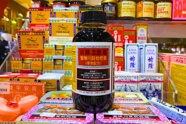 Bottle of Pei Pa Koa cough syrup in front of array of traditional Chinese medicines
