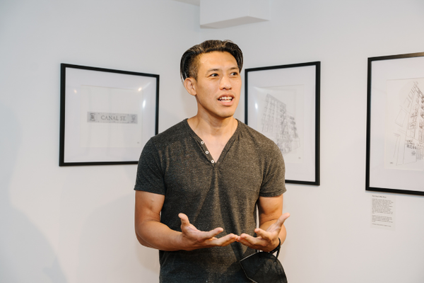 Man speaking in front of framed artwork