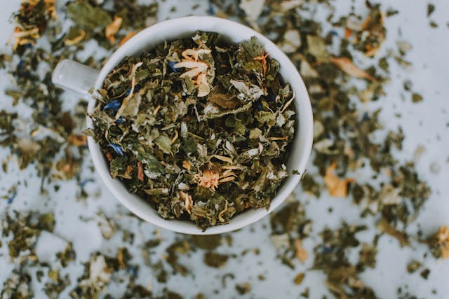 White mug filled with and surrounded by tea leaves