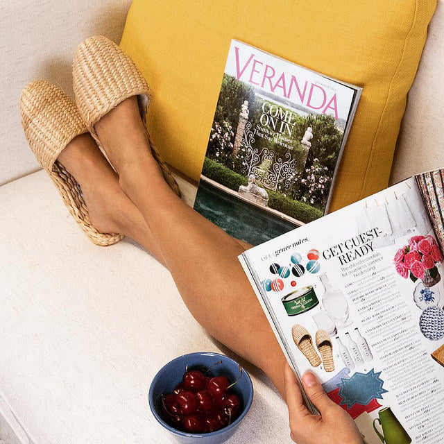 Woman wearing straw slippers with feet up and Veranda magazine