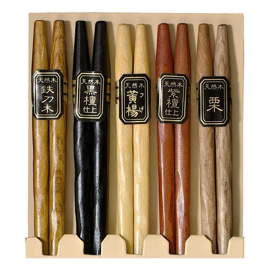 A set of five wooden chopsticks in a light beige cardboard, featuring different natural wood tones and black labels with Japanese characters.