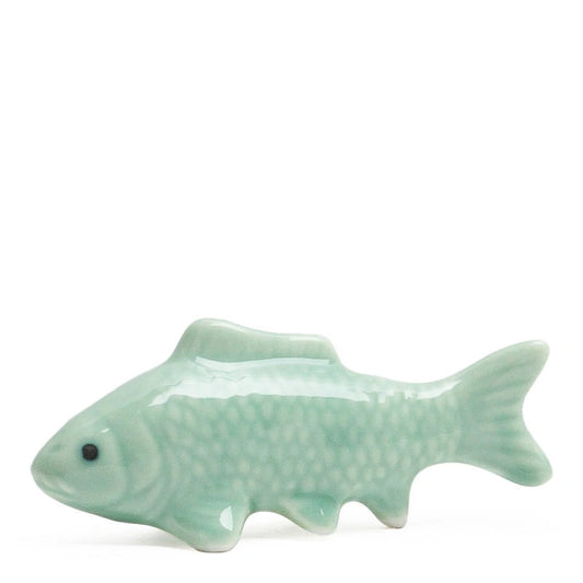 A glossy ceramic fish figurine in a pale mint green glaze, featuring detailed scale patterns and a small black eye, set against a plain white background.