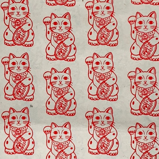 Repeating red-and-white maneki-neko, or lucky cat, illustrations cover a pale background, creating a cheerful, traditional Asian pattern.
