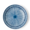 A round ceramic plate with a blue and white radial starburst pattern, photographed from directly above on a white background.