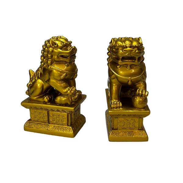 Pair of gold lion statues on decorative bases against a white background