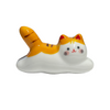 Ceramic cat-shaped object with orange, white, and black colors on a white background.