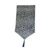Blue and white wave patterned table runner with a blue tassel on a white background