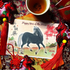 Card with a horse illustration and text 'Happy Year of the Horse' surrounded by decorative items on a patterned fabric background.