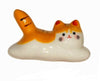 Ceramic cat-shaped object with orange, white, and black colors on a white background.