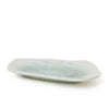 A small, irregularly shaped ceramic dish with a pale sage green glaze, photographed on a seamless white background.