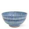 A ceramic bowl with a blue and white striped pattern, featuring vertical ridges on the exterior and a small brown foot ring at the base, set against a plain white background.