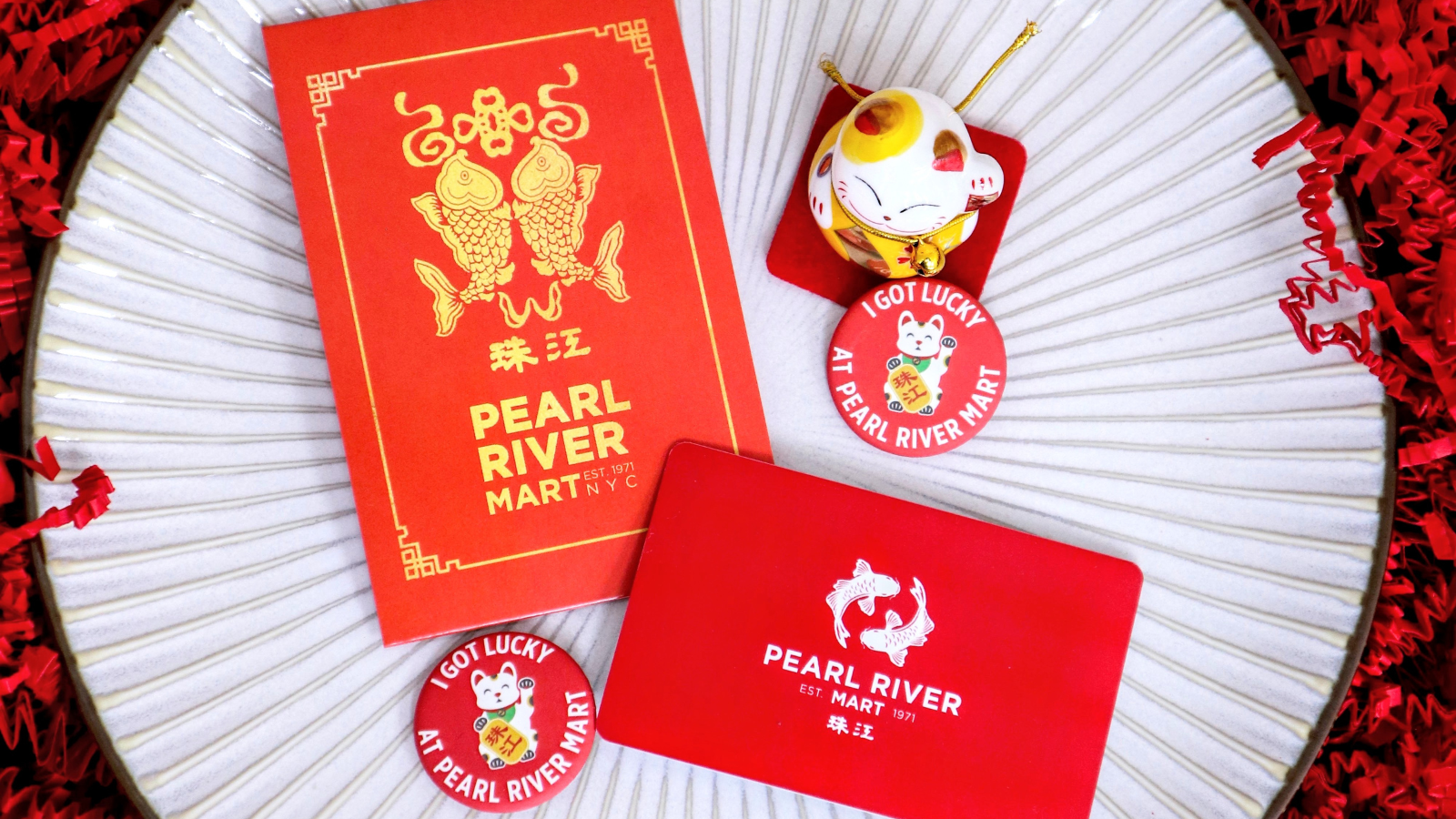 Pearl River Mart gift card with red envelope and ceramic lucky cat on ceramic plate