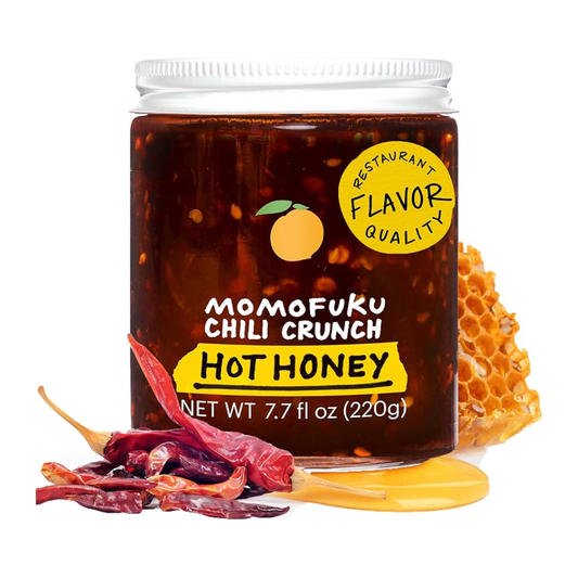 Jar of Momofuku Chili Crunch Hot Honey with chili peppers and honeycomb on a white background