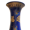 Blue vase with gold and multicolor designs and text, indoor setting
