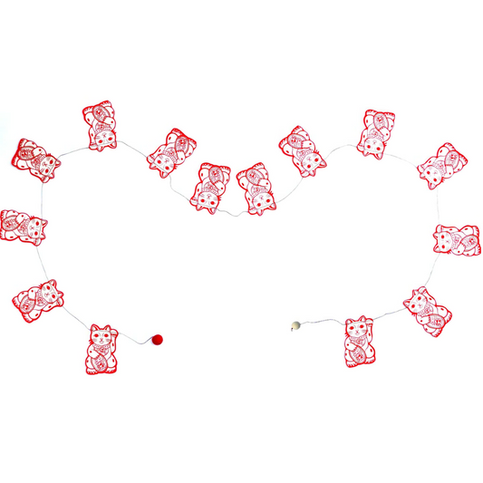 Decorative string with red and white cat-shaped ornaments on a white background