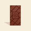 A single dark brown chocolate bar with a textured diamond pattern and an embossed logo in the center, set against a solid cream background with a soft shadow.