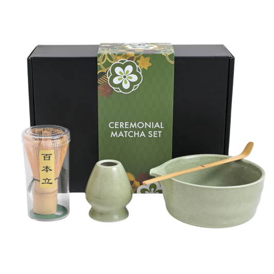 Ceremonial matcha set with green packaging, including a bowl, whisk, and scoop on a white background.