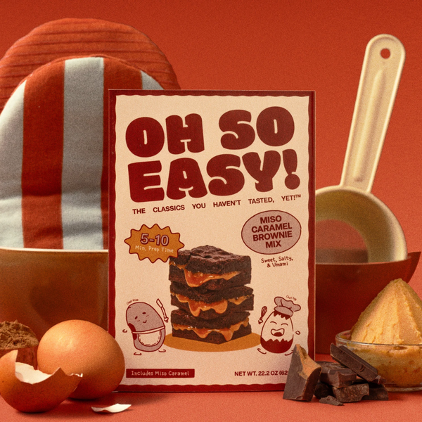 Miso Caramel Brownie Mix packaging with baking ingredients on a red background