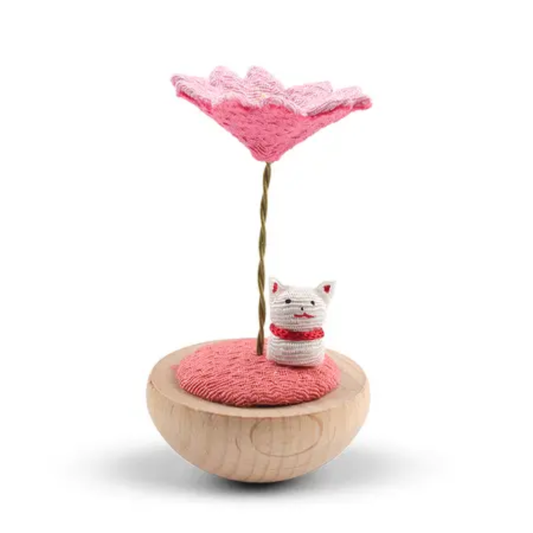 Toy with a pink flower and small white cat figure on a white background