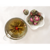 Top view of glass of jasmine blooming tea and small dish of jasmine tea balls